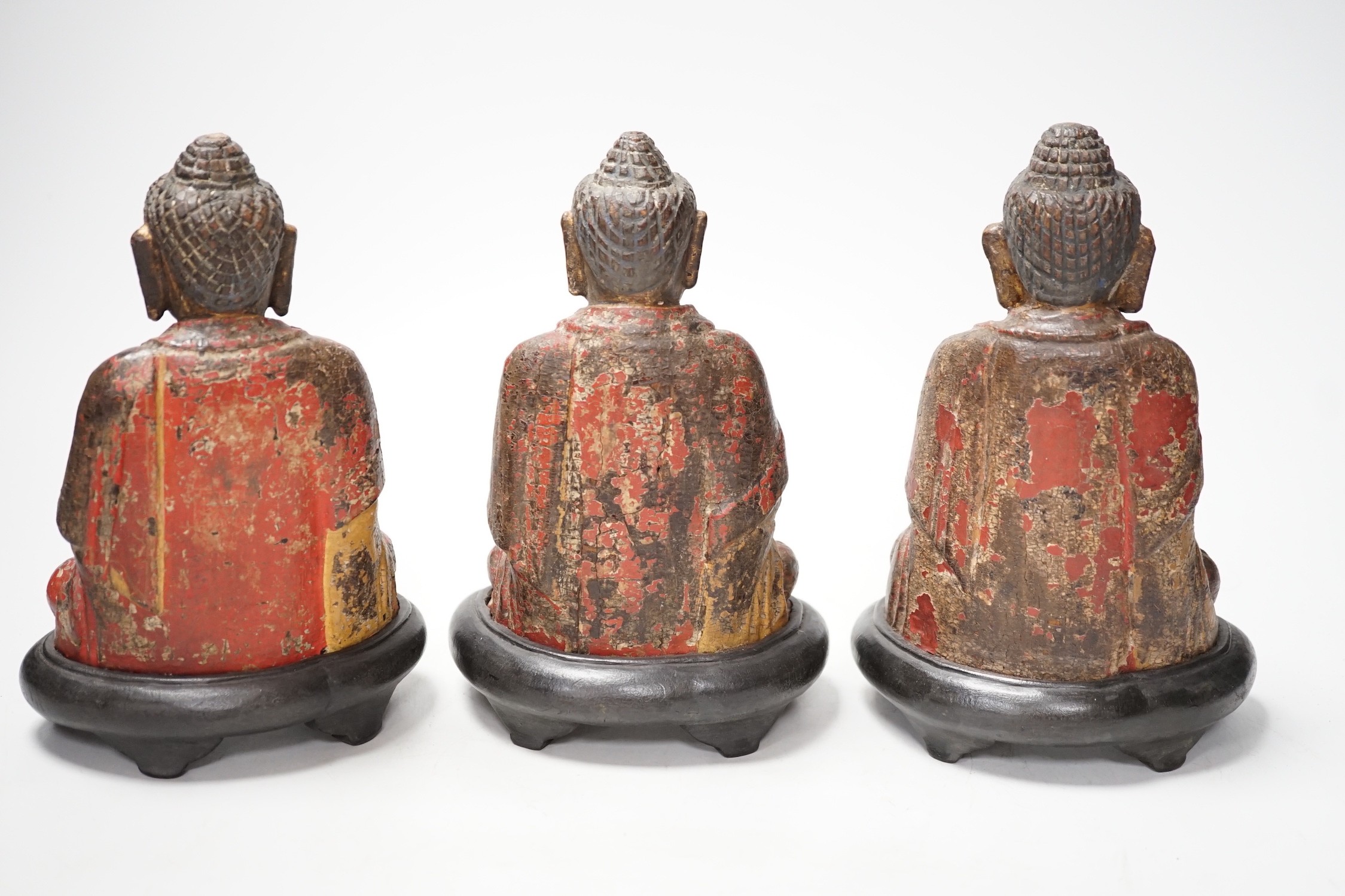 A set of three Chinese polychrome lacquered wood seated figures of Buddha, 19cm